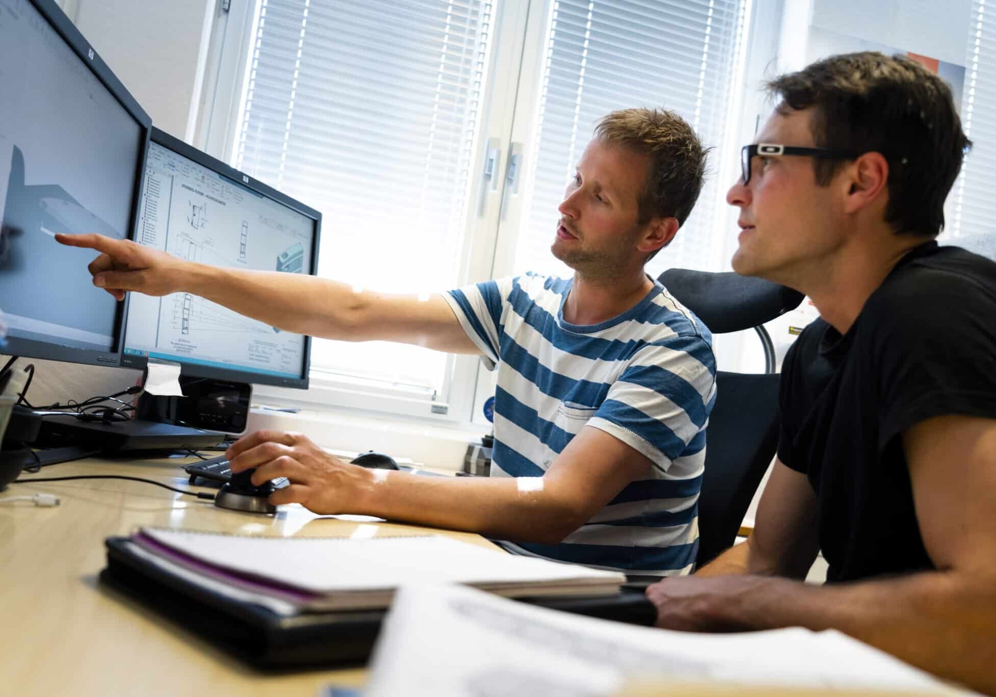 Two engineers looking at 3D models on screen